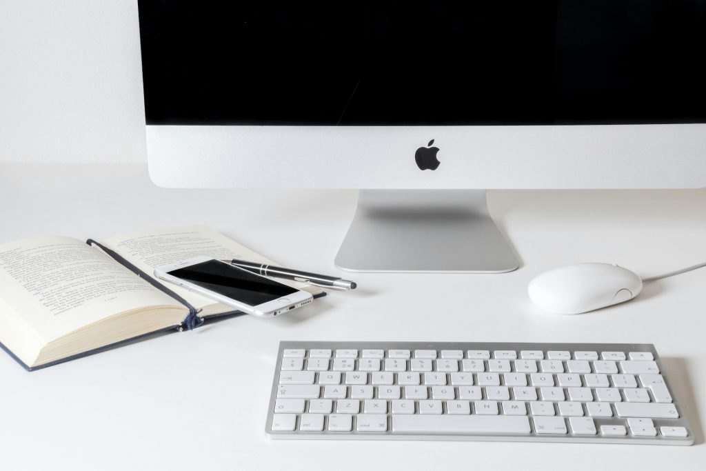 Planung mit iMac, Tastatur, Stift und Buch 